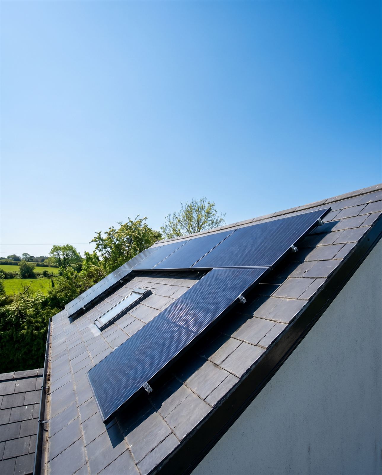 Close-up of EGR solar PV panels on a slate roof with green fields beyond